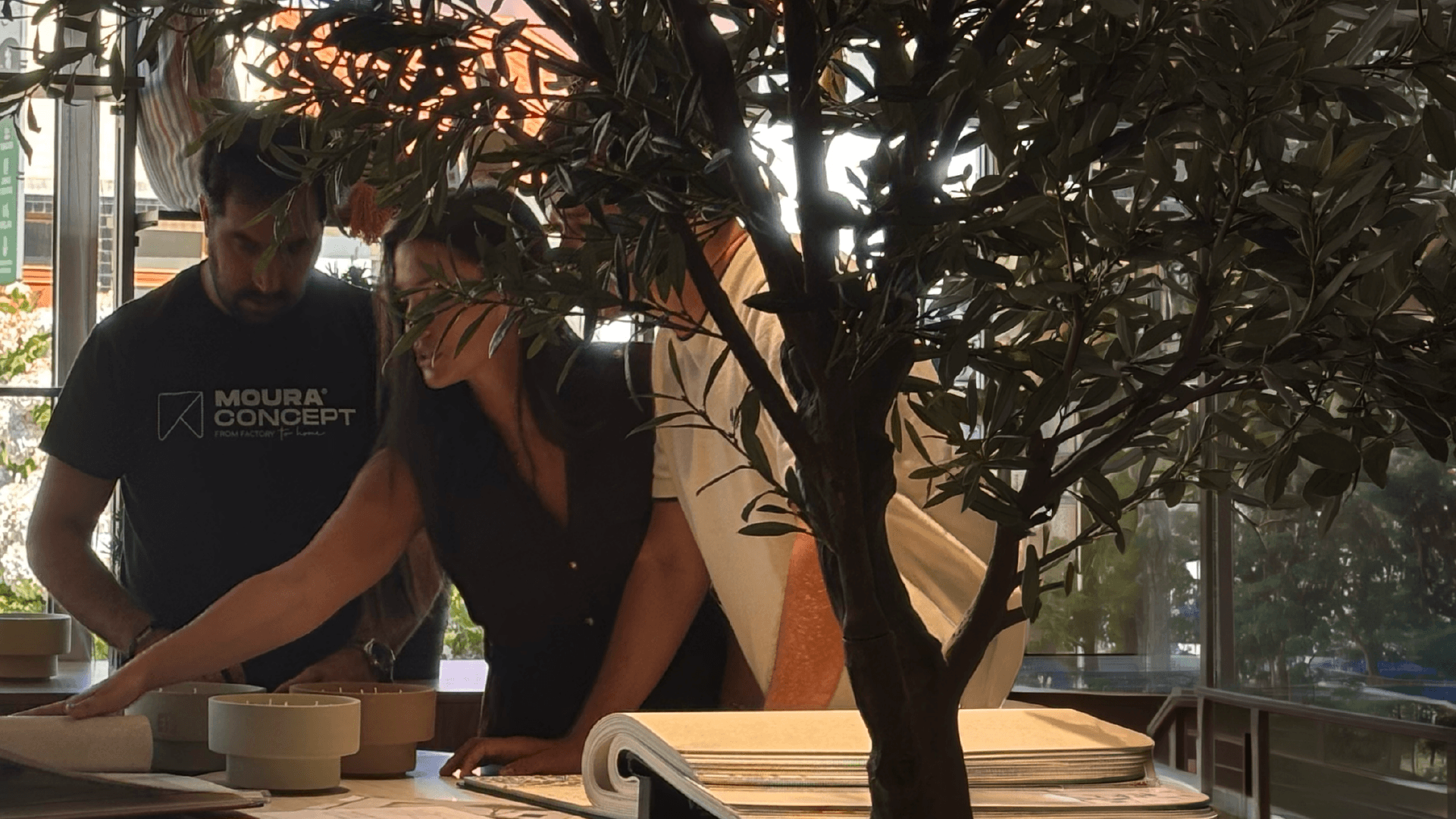 Equipa de designers de interiores da Moura Concept reunida a analisar catálogos de tecidos, acabamentos e materiais para o desenvolvimento de um projeto de decoração e mobiliário personalizado.
