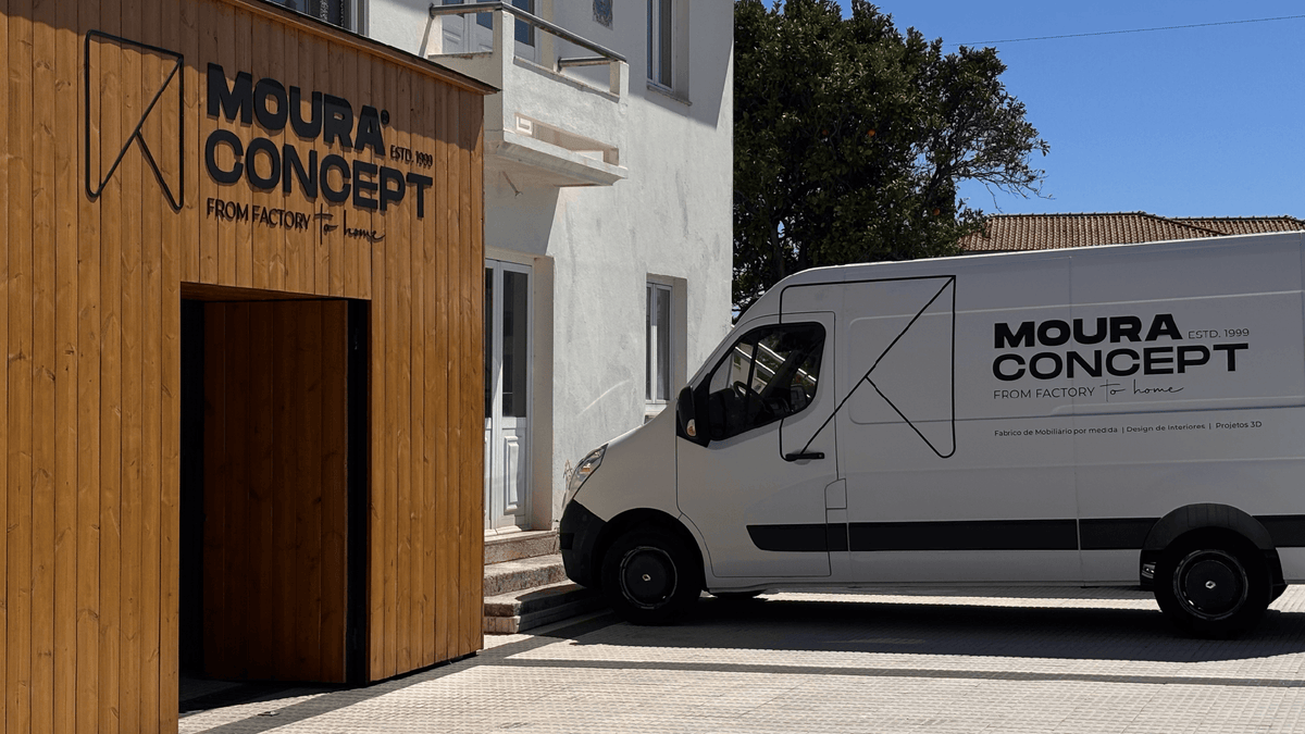Entrada da fábrica e showroom Moura Concept em estrutura de madeira com logótipo corporativo, ao lado da carrinha de entrega e transporte de projetos de mobiliário por medida e design de interiores.