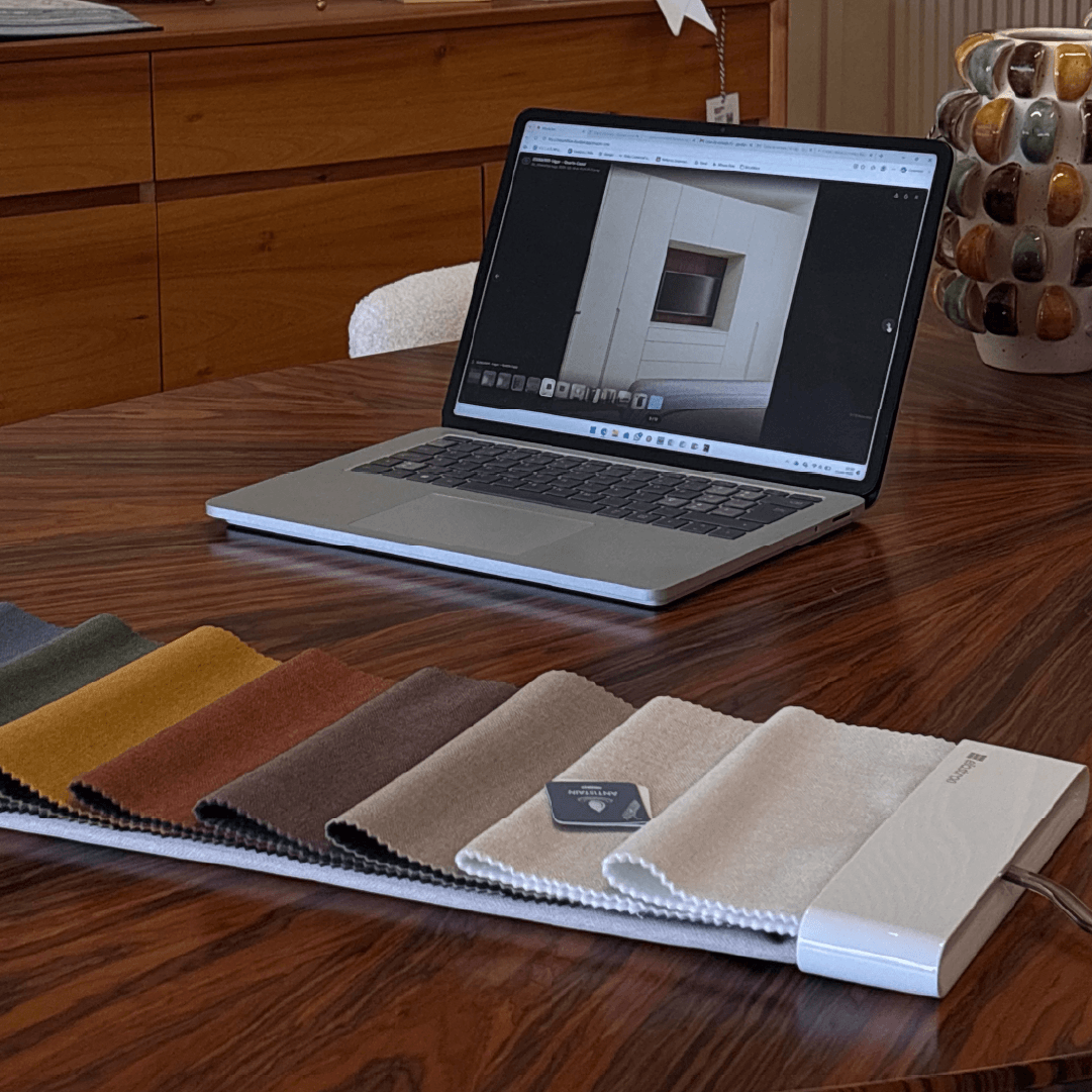 Computador portátil a apresentar renderização de projeto 3D de interiores sobre mesa de madeira, junto a catálogo de amostras de tecidos para estofos e personalização de mobiliário Moura Concept.